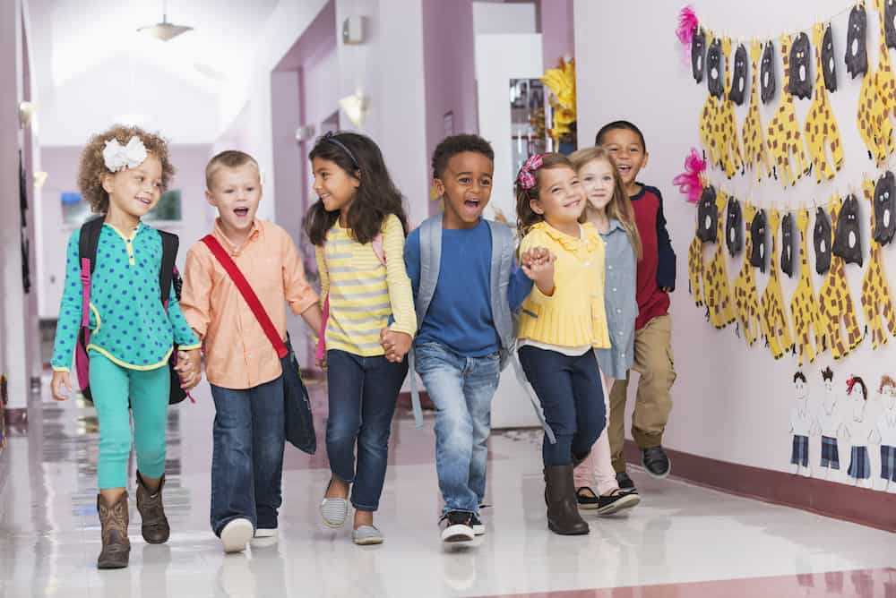 Multiracial group of preschoolers walking down hallway